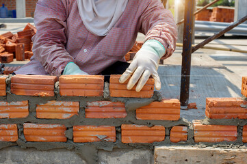 masonry worker make concrete wall by cement block and plaster at construction site