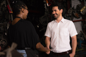 Obraz premium Man shakes hand with woman. Diversity of two people, caucasian business manager smile and shake hand with black African worker woman in factory-warehouse