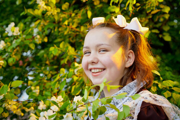 Portrait of a young girl in an old school uniform of the USSR with a black dress and a white apron. Teenager in the Park among the greenery after graduating from school in Russia