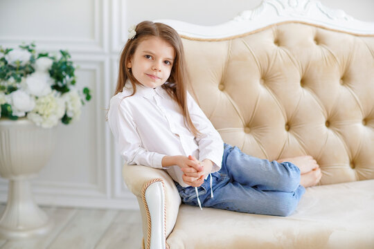 Little cute girl lies on the sofa in the room