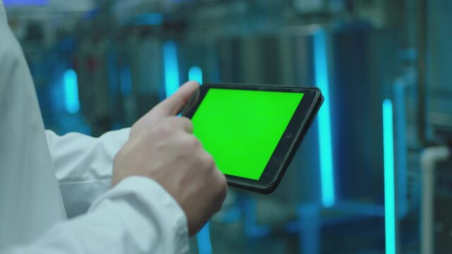 Male artist using black tablet with green screen or chroma key screen and doing notes in slow motion .  Close up man's hand  touching gadget screen inside factory or laboratory  .  Working process 