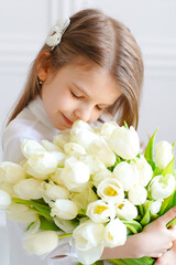 Obraz na płótnie Canvas Portrait of beautiful pretty girl with white flowers tulips sitt