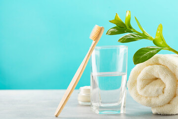 A bamboo toothbrush, a glass of water, a white cotton towel and toothbrush powder in a jar. Biodegradable personal care products. No plastic concept