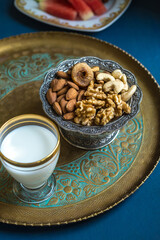 Bowl of assorted dry fruits containing healthy and nutritious almonds, digs, cashew and walnuts. Glass of milk served in a tray with mixed nuts- a power snack.