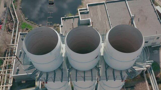 4K footage of non-smoking three chimneys of a thermal station with cinematic movement with the ending against the background of the city. packshot with pipes. Industrial city in summer. Aerial view.