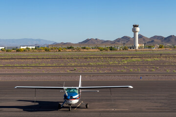 Small private airplane during early morning hours at airport with control tower in background