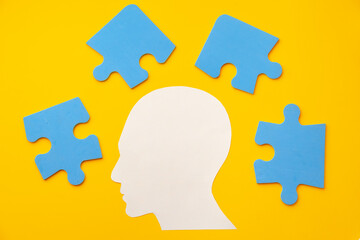 Papercut head silhouette with puzzle pieces on yellow background