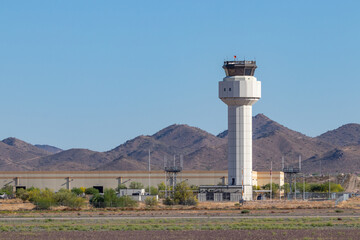 Air traffic control tower at a small airport against a blue sky with surrounding mountains © Cynthia