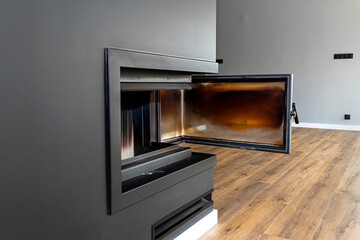 Open, dirty corner pane in a modern fireplace with a closed combustion chamber standing in the...
