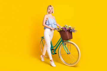 Full body profile photo of positive blond hair lady ride bicycle wear top pants isolated on yellow...