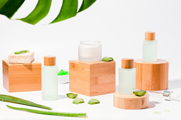 Natural cosmetics with aloe on wooden podiums in reusable bottles