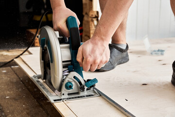 Sawing plywood by circular saw. Home repair. Hand tool. Man hold equipment. Building process....