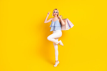Full size photo of funny blond hair lady hold bags wear spectacles top pants isolated on yellow background