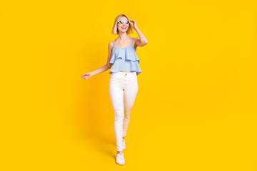 Fototapeta na wymiar Full size photo of pretty blond short hair lady go wear spectacles top pants isolated on yellow color background