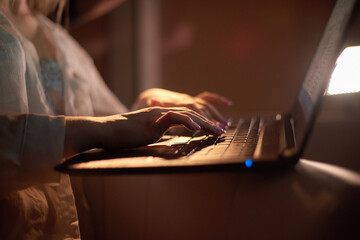 close up shallow depth of field photo of woman hands typing on a laptop keyboard at night