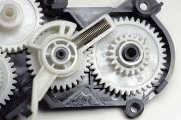 multiple reducer gears of white plastic, spring and black case - parts of inkjet printer paper feeder mechanical drive
