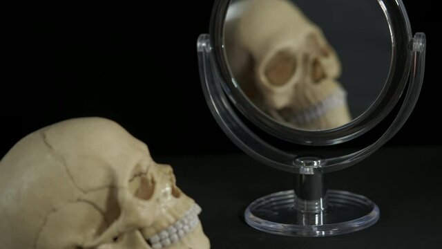 In pursuit of beauty in mirror. A human skull in pursuit of beauty and look in the mirror.
