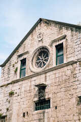 Round rose window on an old building with sculptures against a blue sky