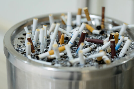 Closeup of many cigarettes butts in a tray with sand