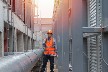 workers on site. worker using radio communication on piping plant of cooling tower.