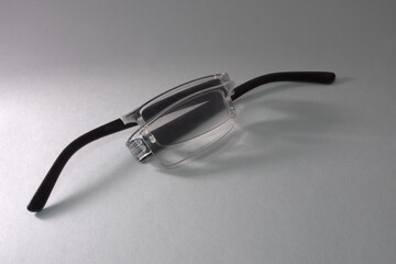 folded reading glasses, broken in half along the bridge between the lenses