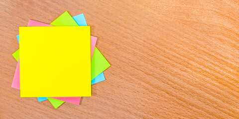 On a wooden table there are multicolored stickers with a place to insert text. Template. Copy space