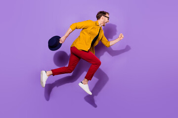 Fototapeta na wymiar Full size profile side photo of cheerful crazy young man jump up run empty space isolated on violet color background