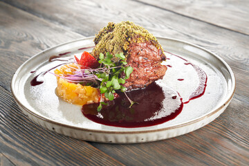 Close up view of beef meat with pistachio topping served with cranberry sauce. Tasty meal with...