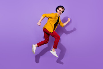 Full side profile side photo of young guy happy positive smile go walk run fast jump isolated over purple color background