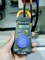 Inspection and measurement of electrical systems with meters in industrial plants.  Measuring the current from the circuit breaker with an electric meter.  Clamp meter