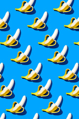 Peeled banana pattern in hard light on blue background