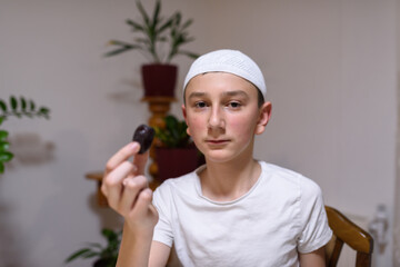 Happy young Muslim boy eating a dates ready for iftar in Ramadan.