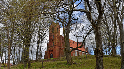 Fototapeta na wymiar Built at the end of the 14th century in the Gothic style of red brick and stones, St. John's Catholic Church in the village of Czerniki in Masuria, Poland. The photos show a general view of the temple