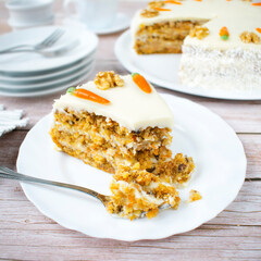 Homemade carrot cake with coconut cream. Structured cake with walnuts, pineapple and coconut flakes on a wood background.