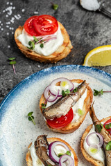Sandwich smorrebrod with sprats, tomatoes and cream cheese. Food recipe background. Close up