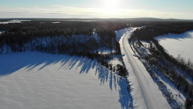 Beautiful Scenery Of Frozen Road Between a Lush Forest In Lapland Finland In Winter - aerial shot