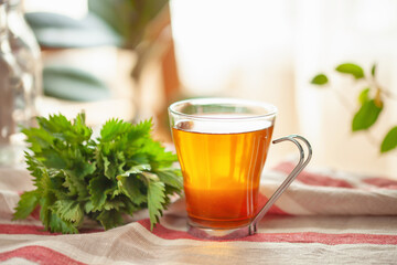 Herbal nettle tea in a glass cup on the table.