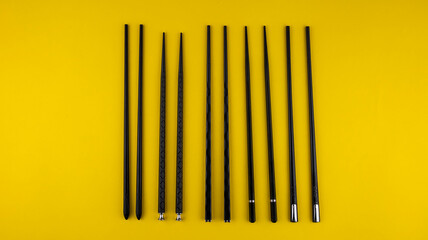 set of black sushi chopsticks on yellow background, isolated