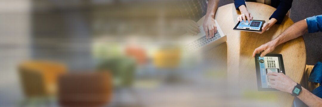 Mid section of colleagues working on digital tablet on desk at the office