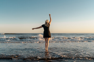 Fototapeta na wymiar Happy woman on vacation dancing on the seashore at sunset