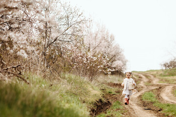 Naklejka na ściany i meble Little girl in rubber boots running on a dirt path in countryside on spring day.