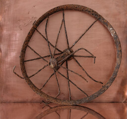Old rusty wheel from a pram on a copper background.