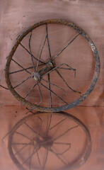 Vintage rusty wheel from a pram on a copper background. Reflection. Vertical image. Copy space. 