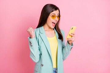 Photo portrait of excited amazed woman celebrating holding phone in one hand isolated on pastel...