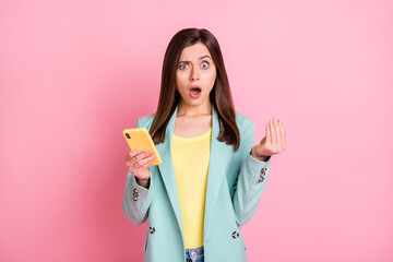 Photo portrait of confused woman showing italian hand sign holding phone in one hand isolated on pastel pink colored background