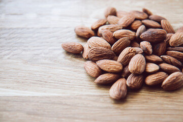 Crude almonds nuts on wooden background. Healthy eating concept. Side view