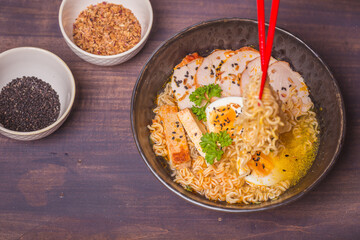 Ramen Soup with chicken in Bowl on wooden table. Beef ramen served Asian style. Raw egg cooks in steaming hot savory broth.