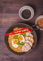 Ramen Soup with chicken in Bowl on wooden table. Beef ramen served Asian style. Raw egg cooks in steaming hot savory broth.