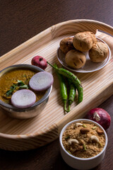 Traditional Rajasthani cuisine daal bati served on a wooden tray along with onion and daal bati churma