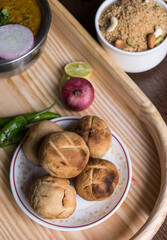 Traditional Rajasthani cuisine daal bati served on a wooden tray along with onion and daal bati churma
